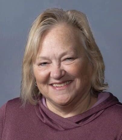 A woman with blonde hair wearing a purple shirt.