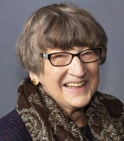 A woman with glasses and a scarf around her neck.