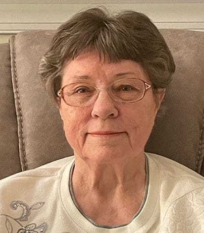 A woman with glasses sitting on top of a chair.