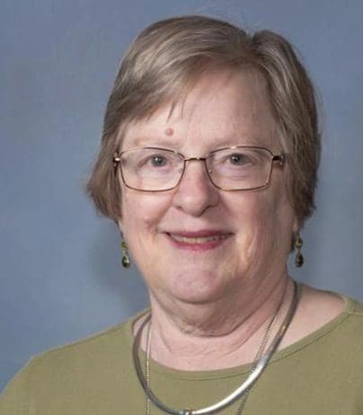 A woman with glasses and short hair wearing a necklace.