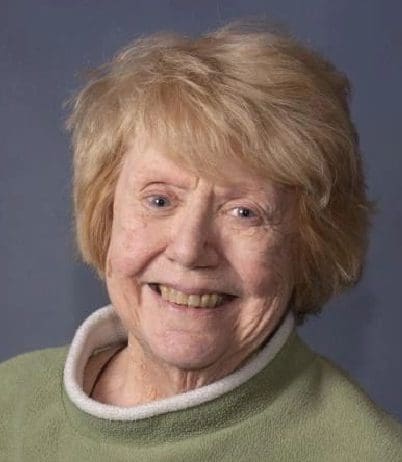 A woman with blonde hair and green shirt smiling.