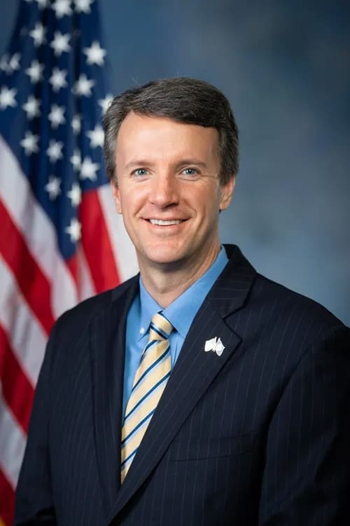 A man in suit and tie next to an american flag.